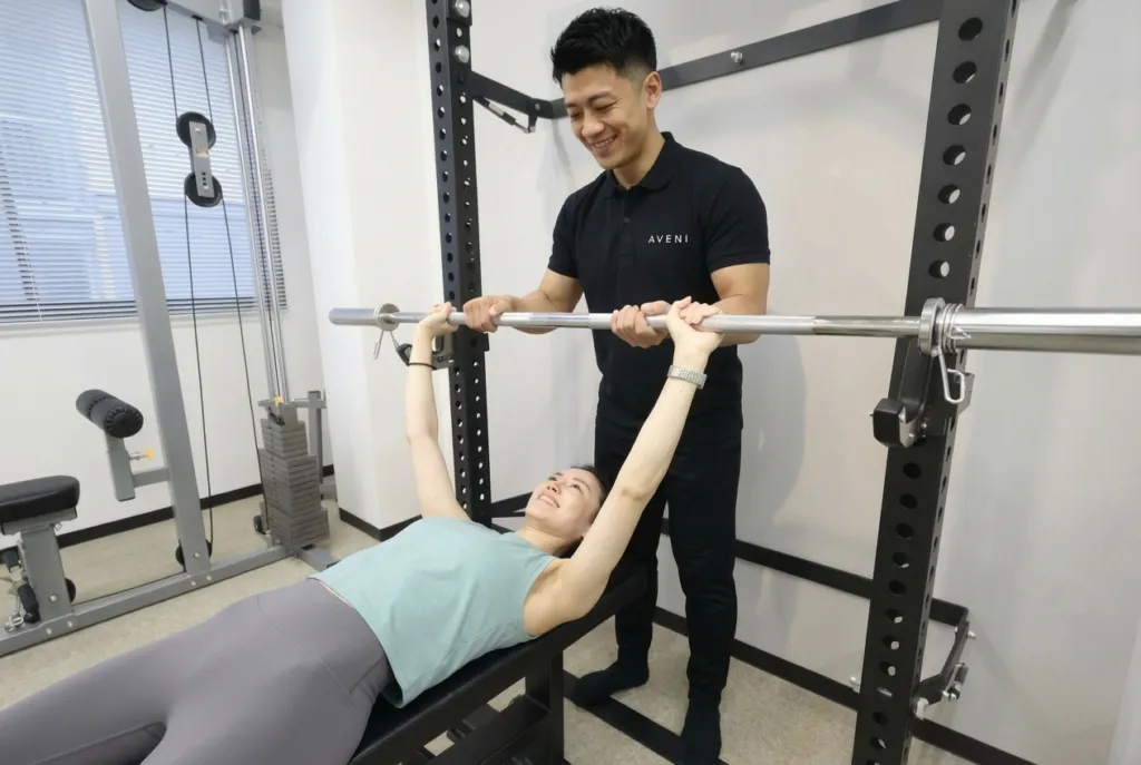 アヴニールのトレーナーがベンチプレスを補助する様子