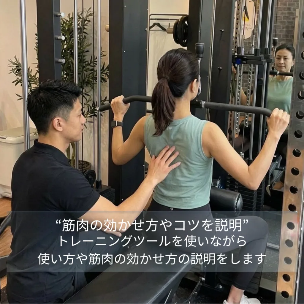 トレーナーがマシンの使い方と筋肉の効かせ方を説明する様子